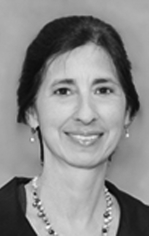 ChiarelloLisa_cropped Black and white portrait of a woman with dark hair, wearing a necklace and earrings, smiling slightly at the camera.