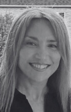Diana_Parvinchi A woman with long straight hair smiles at the camera; the image is in black and white with a blurred outdoor background.