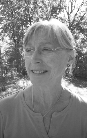 Jan_Burke-Gaffney An older woman with glasses and short hair smiles slightly while standing outdoors on a sunny day.